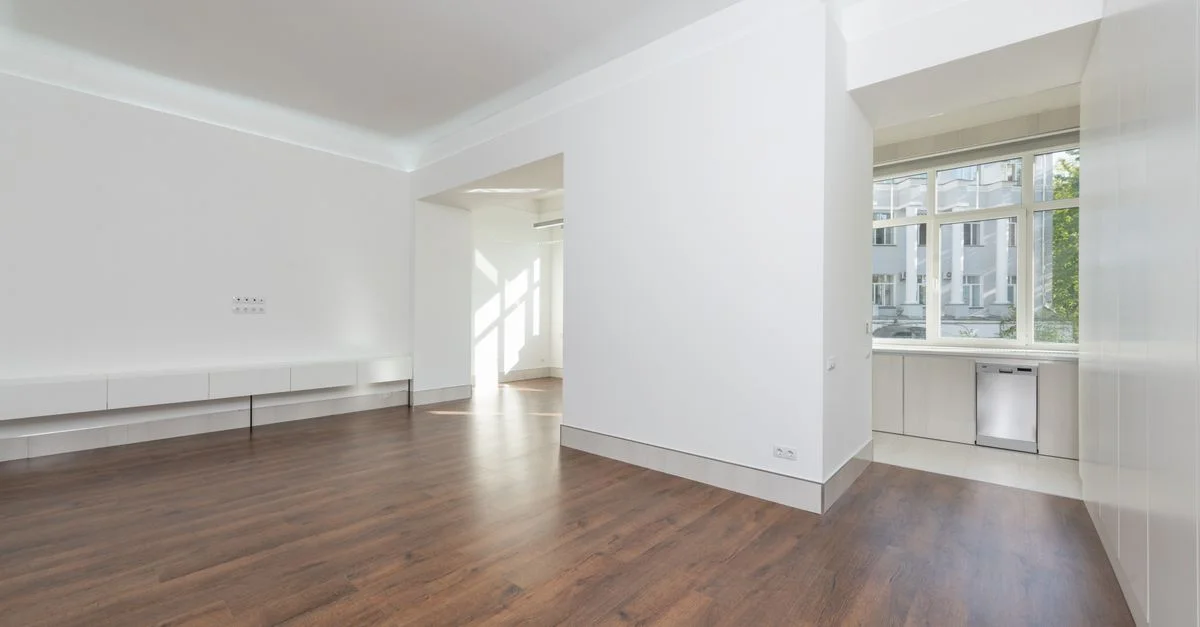 Un appartement contemporain vide avec des murs blancs et un sol en bois, featuring de grandes fenêtres.